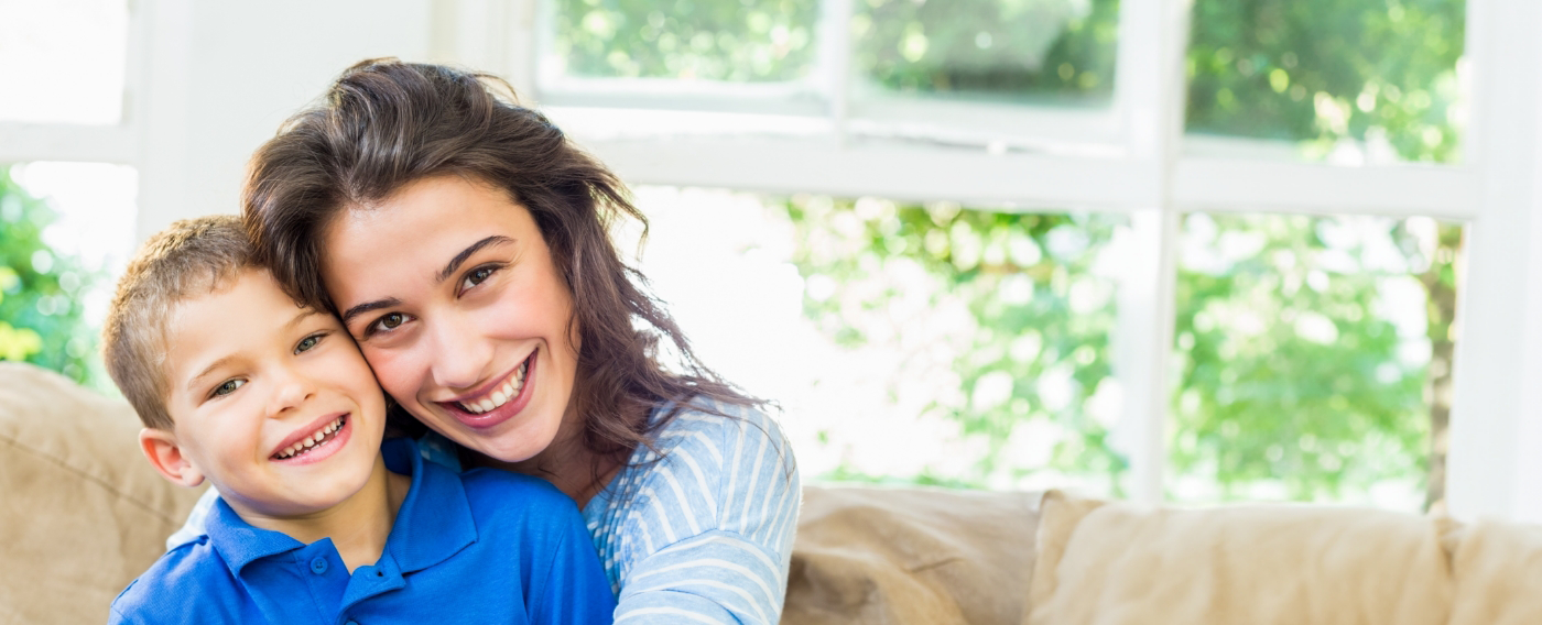 Smiling mother and child hugging after lip and tongue tie treatment