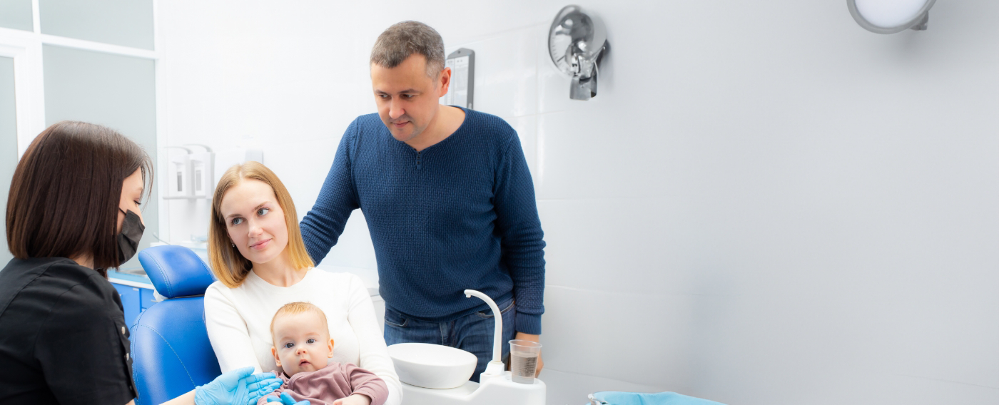 Mother and father talking to dental team member with their baby