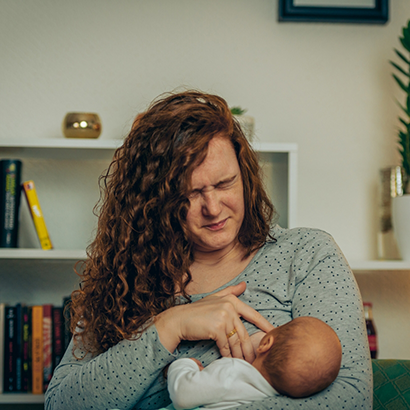 Mother wincing while breastfeeding her baby