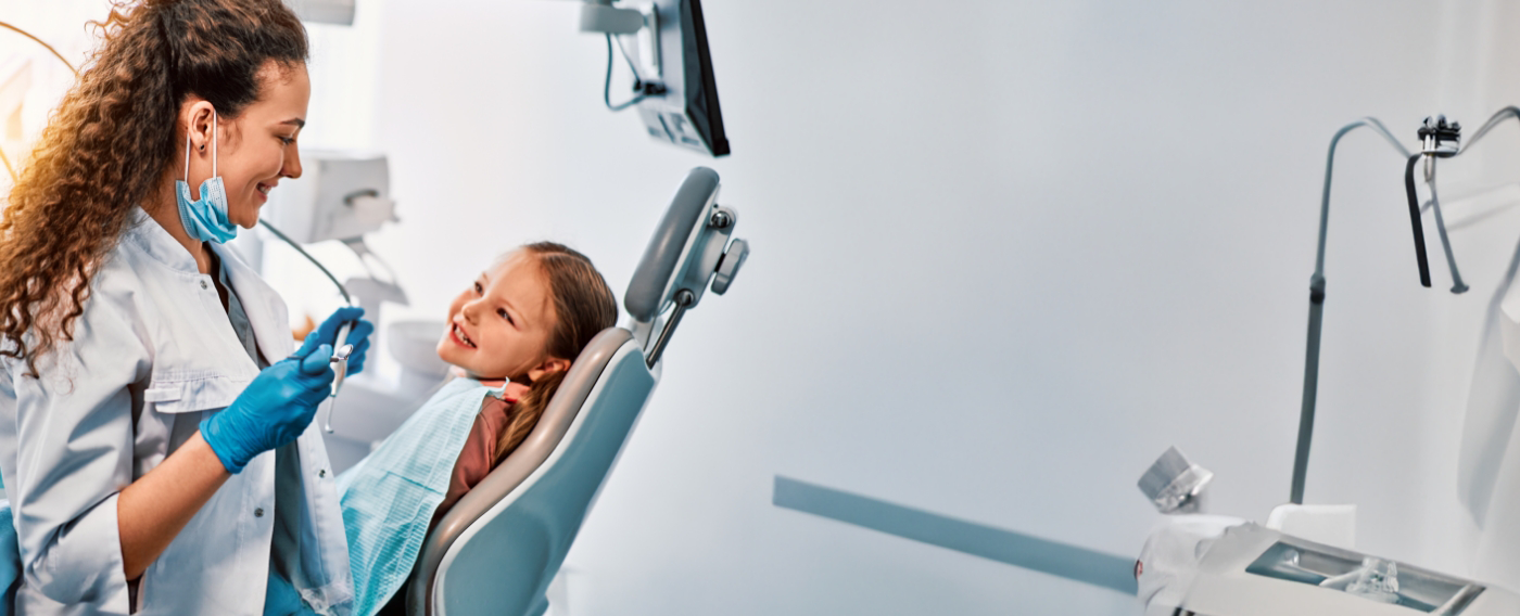 Young girl in dental chair smiling at her pediatric dentist in Boulder