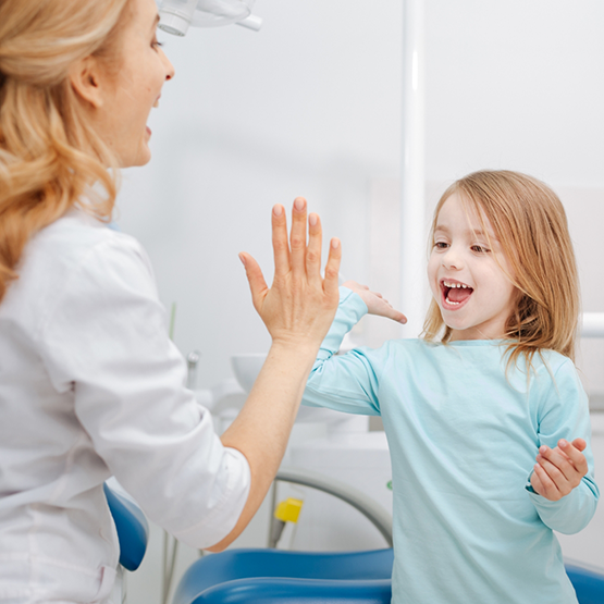 Young girl giving a high five to her dentist