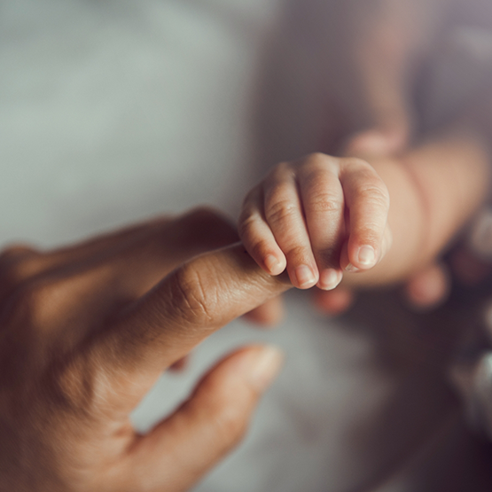 Baby holding onto an adults finger