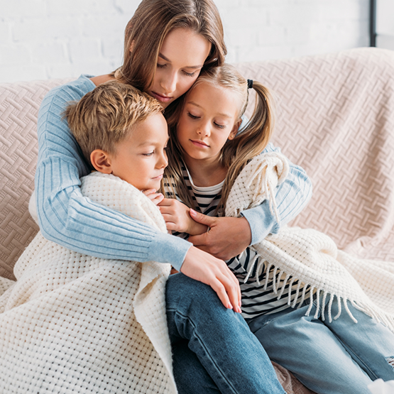 Mother sitting on couch and holding her two children