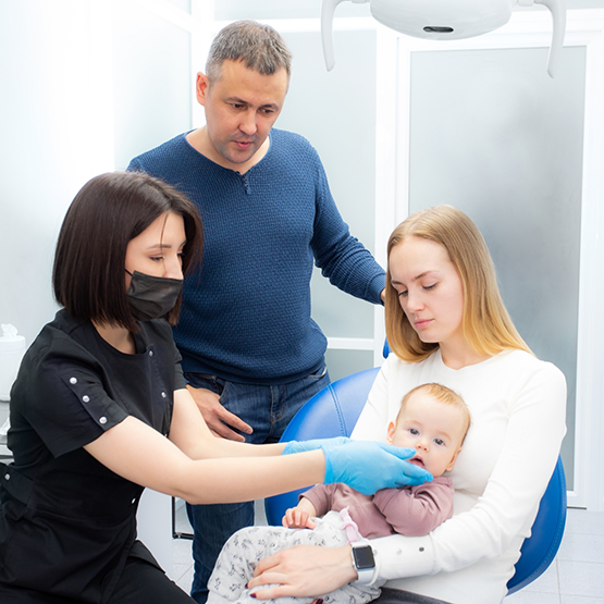 Mother and father with their baby in dental office after laser frenectomy