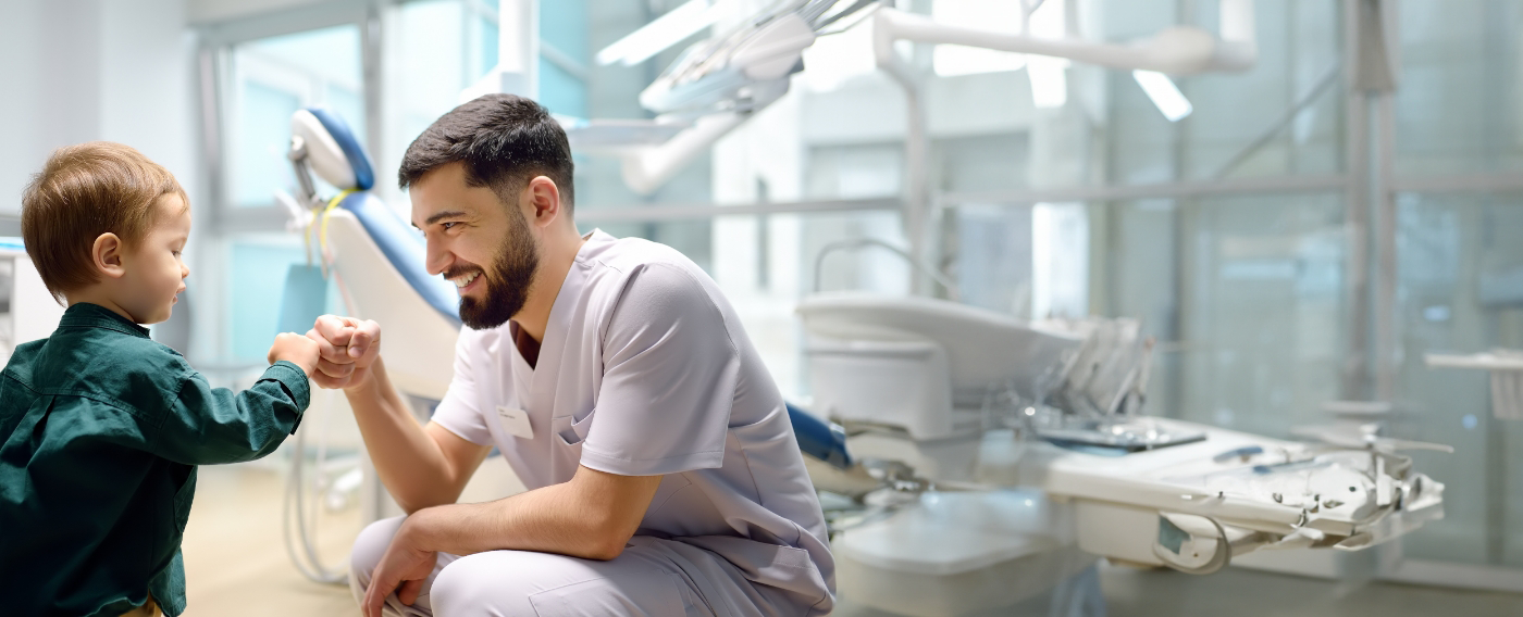 Pediatric dentist smiling and doing a fist bump with a child patient