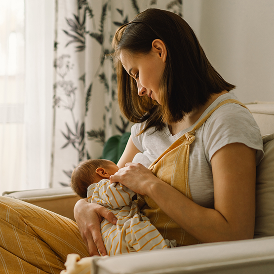 Mother breastfeeding her baby at home