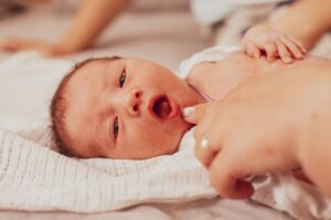 Mother opening her baby’s mouth to look at their tongue